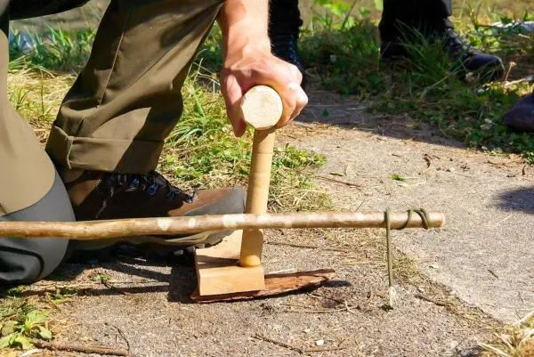 Holzstück mit Kerbe wird mit einem Stock bearbeitet