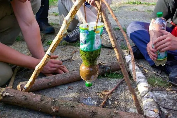 Improvisierte Wasserfilterkonstruktion aus einer Plastikflasche und Ästen