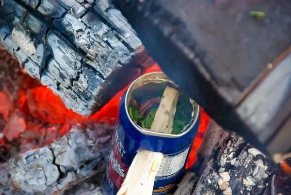 Kessel mit Zunder und Holzstück über Glut platziert