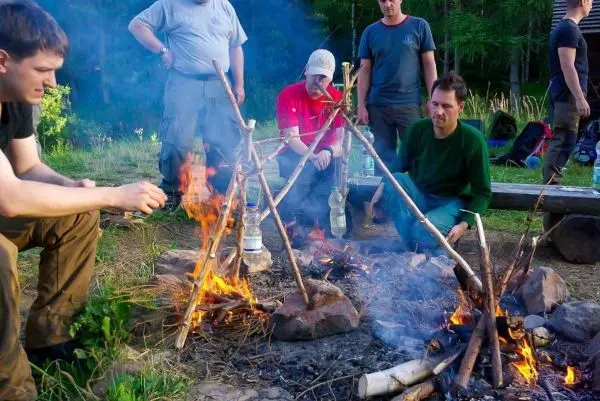 Kleine Flamme brennt unter einem improvisierten Kocher aus Ästen