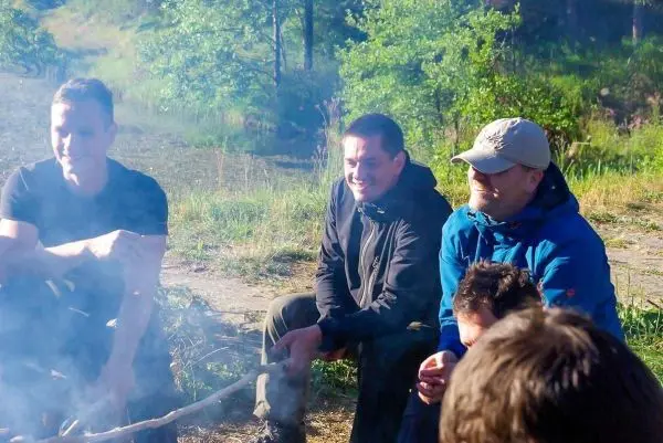 Kleine Flamme glimmt zwischen mehreren Personen am Boden