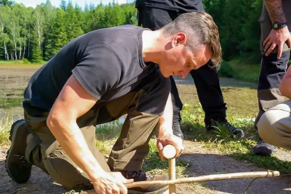 Mann bearbeitet Holzstück mit einem Messer zur Herstellung eines Werkzeugs