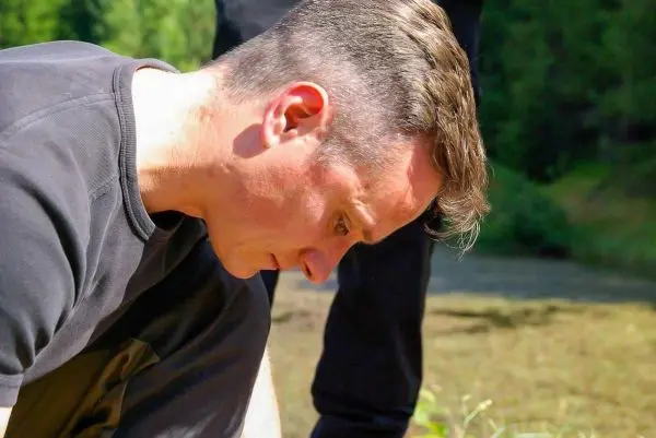 Mann beugt sich über den Boden, möglicherweise um etwas zu untersuchen