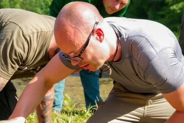 Mann beugt sich über den Boden und untersucht die Umgebung