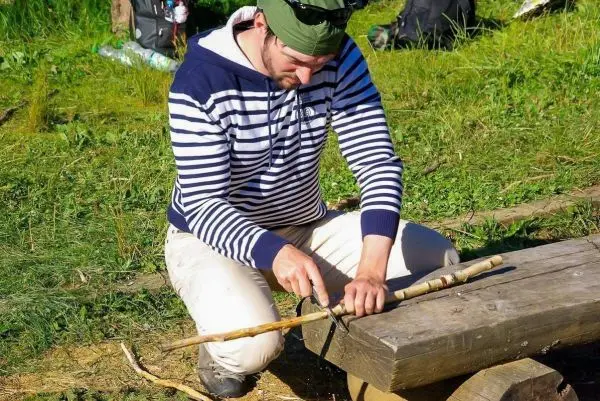 Messer bearbeitet Holzstück auf einer Holzbank im Freien