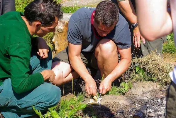 Messer schneidet Zunder auf dem Boden neben einer kleinen Feuerstelle