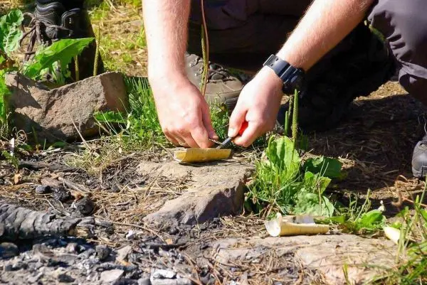 Messer schneidet Zunder auf einer improvisierten Unterlage aus Holz