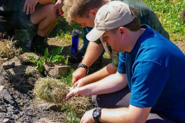 Person formt Zunder aus Gras und Erde