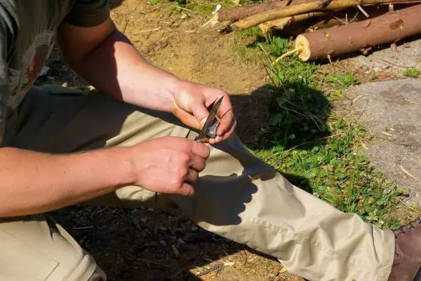 Person schneidet mit einem Messer einen Stock