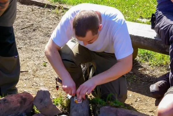 Person schnitzt mit einem Messer an einem Stein