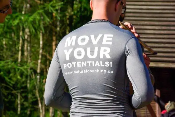 Person trägt ein graues Shirt mit Aufdruck auf dem Rücken