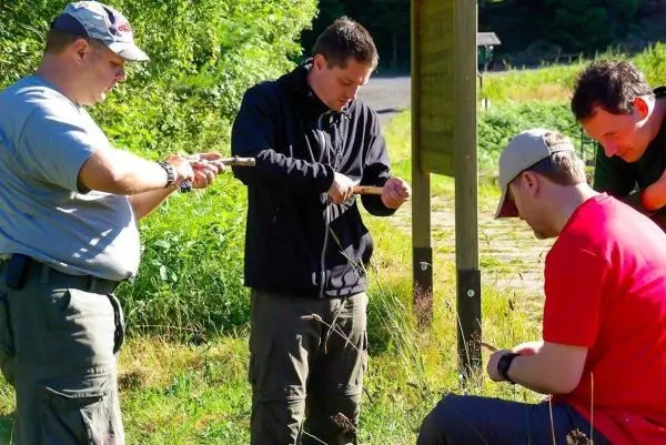 Vier Personen arbeiten gemeinsam an einer Holzarbeit im Freien