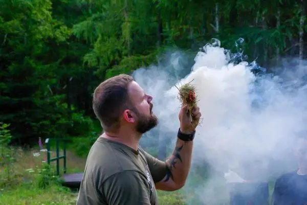 Zunder glimmt in der Hand, Rauch steigt auf