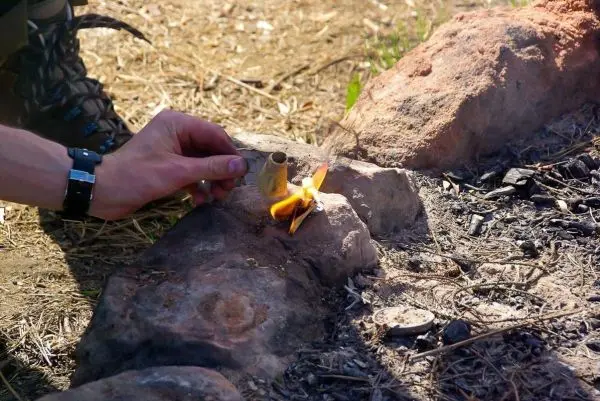 Zunder glimmt in einer kleinen Flamme zwischen Steinen