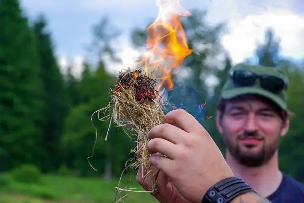 Zunder glimmt und erzeugt kleine Flammen in der Hand