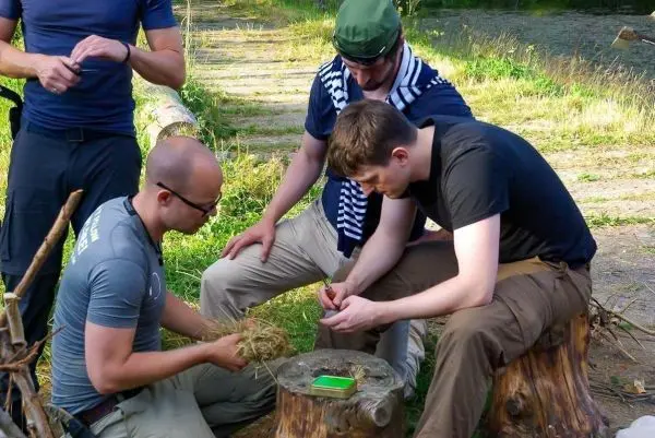 Zunder wird vorbereitet, während zwei Personen zuschauen und unterstützen