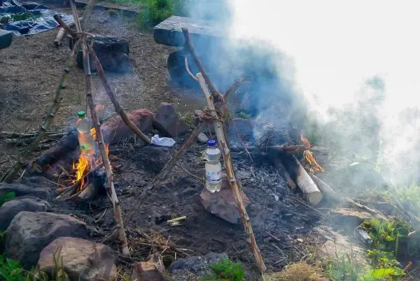 Zwei kleine Feuer brennen unter improvisierten Kesseln aus Flaschen