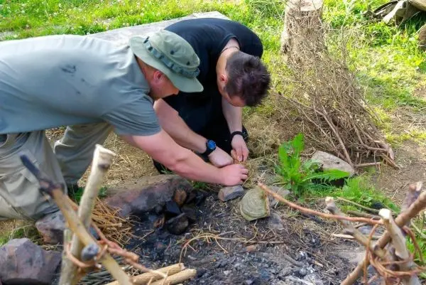 Zwei Personen bereiten ein Feuer im Freien vor