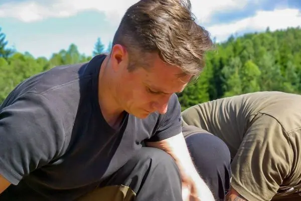 Zwei Personen knien am Boden und konzentrieren sich auf eine Tätigkeit im Freien