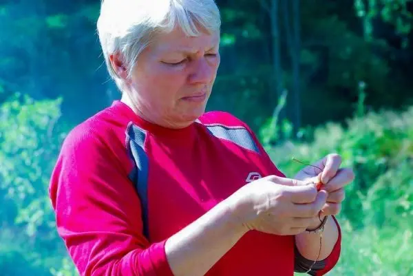 Frau knüpft eine Schnur mit beiden Händen im Freien