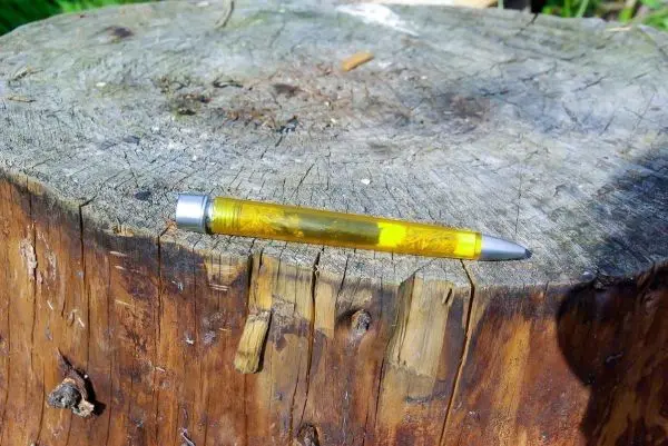 Gelber Kugelschreiber liegt auf einem Baumstumpf