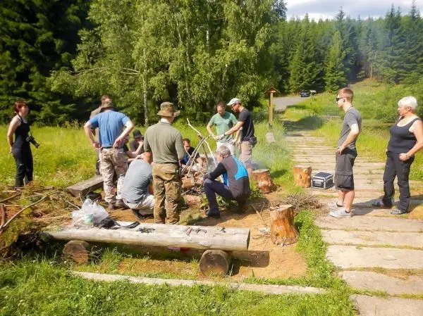 Gruppe arbeitet an einer Feuerstelle mit Holz und Werkzeugen im Freien