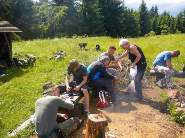 Gruppe arbeitet gemeinsam an einem Holzstück im Freien