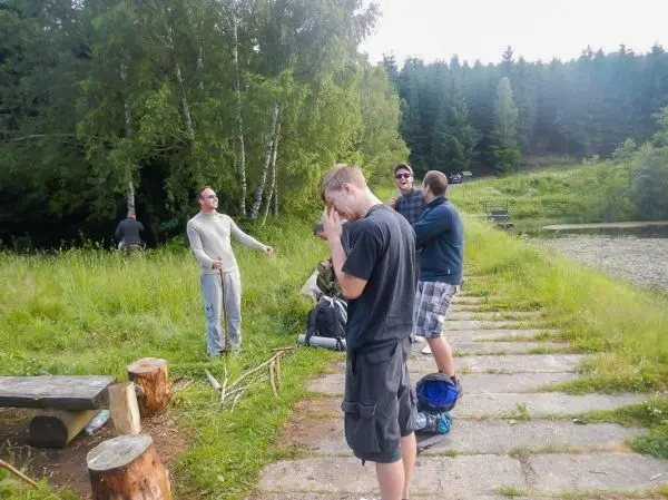 Gruppe steht auf einem Weg, einige halten Stöcke und Rucksäcke