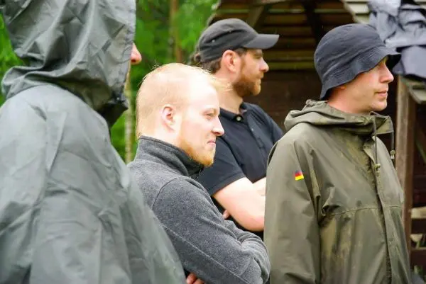 Gruppierung von Personen in wetterfester Kleidung, einige mit Kapuzen, stehen nebeneinander