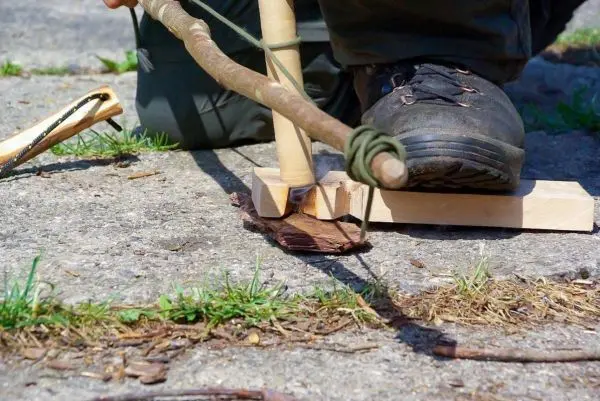 Holzstück wird mit einem Stock bearbeitet, um Feuer zu erzeugen