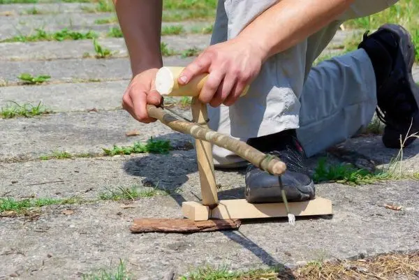 Holzstück wird mit einer selbstgebauten Feuerbohrvorrichtung bearbeitet