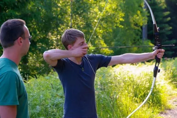Junge spannt einen Bogen und zielt auf ein Ziel