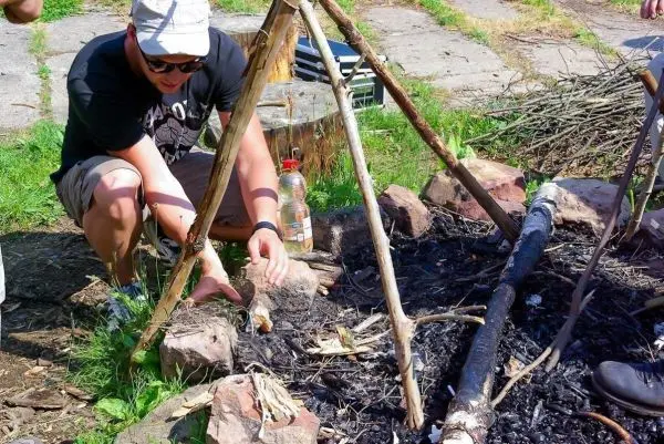 Kessel über Feuerstelle mit Steinen und Holzgestell vorbereitet