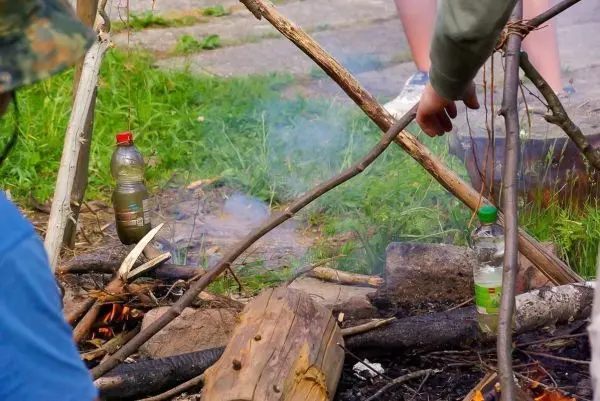 Kleine Flamme erzeugt Rauch zwischen Holzstücken und Flaschen
