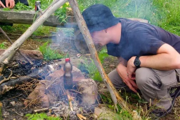 Kleine Flamme glimmt zwischen Steinen, Rauch steigt auf