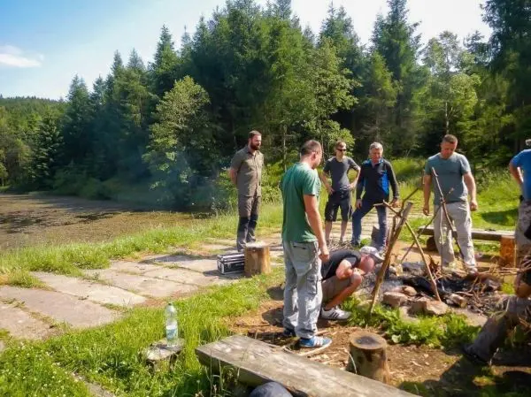 Kleines Bodenfeuer mit Holzgestell in einer Gruppe umgeben von Bäumen