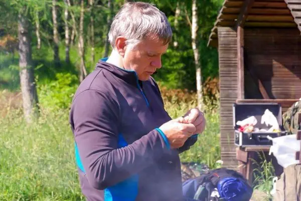 Mann bereitet Zunder in der Nähe einer Holzunterkunft vor