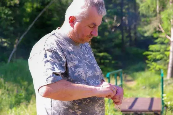 Mann knotet eine Schnur im Wald, um eine Konstruktion vorzubereiten