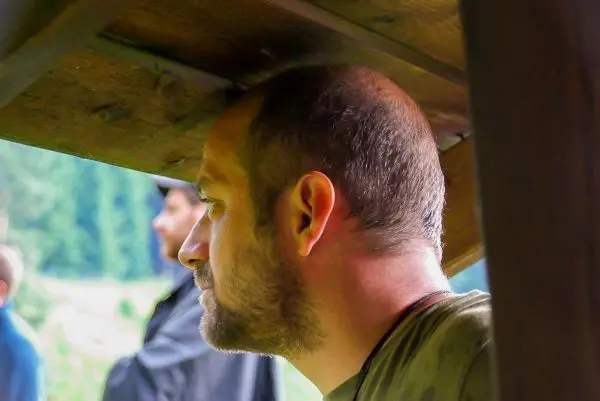 Mann schaut nachdenklich unter einer Holzstruktur hindurch