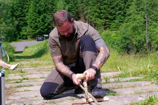 Messer bearbeitet Holzstück auf einem Steinweg im Freien