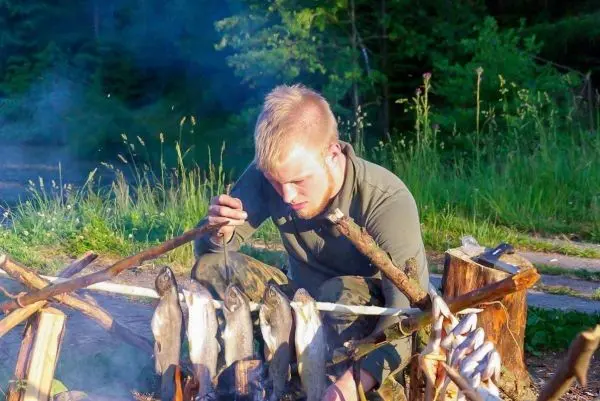 Person grillt Fisch über offenem Feuer