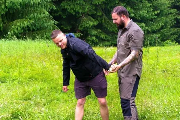 Person hält andere Person am Handgelenk im Gras