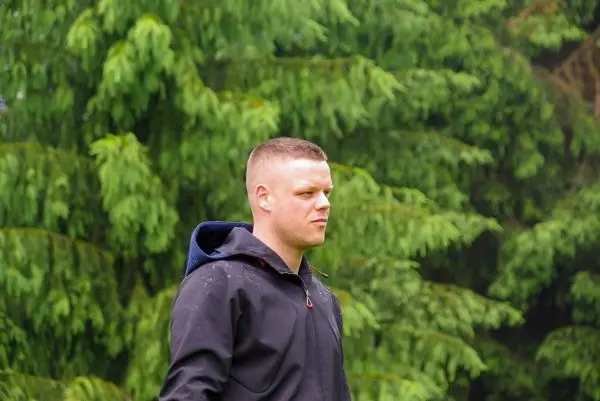 Person steht vor gruenen baeumen