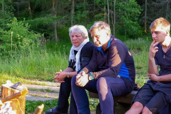 Sitzende Personen am Lagerfeuer in einer grünen Umgebung