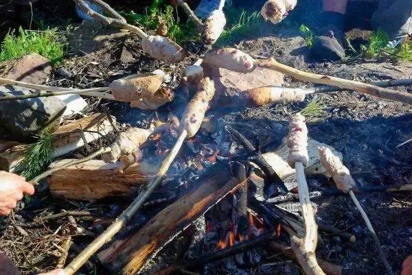 Stöcke mit Teig über offenem Feuer zum Backen gehalten