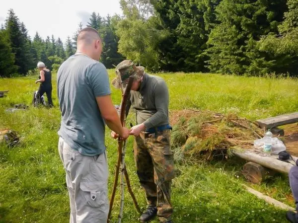Zwei Personen bauen eine selbstgebaute Konstruktion aus Ästen im Freien