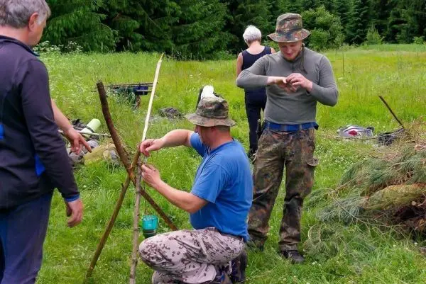 Zwei Personen bauen eine selbstgebaute Konstruktion aus Ästen im Gras