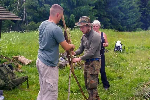 Zwei Personen bauen eine selbstgebaute Konstruktion aus Holzstöcken im Freien