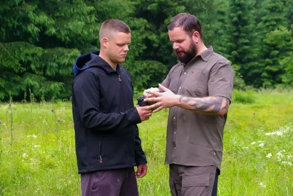 Zwei Personen stehen in einer Wiese und betrachten ein Gerät