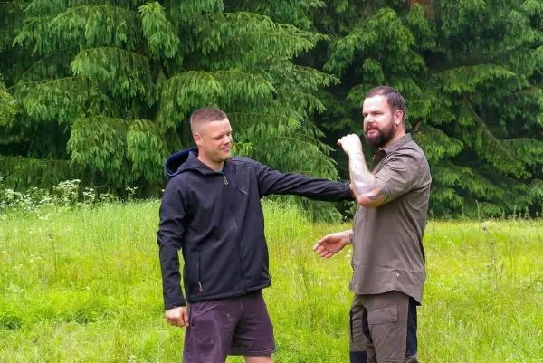 Zwei Personen stehen in einer Wiese und führen eine körperliche Übung durch